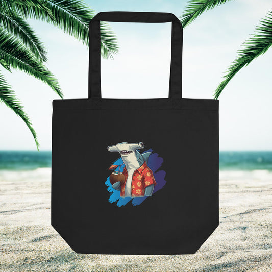 black eco friendly tote bag with a hammerhead shark logo on a sandy beach