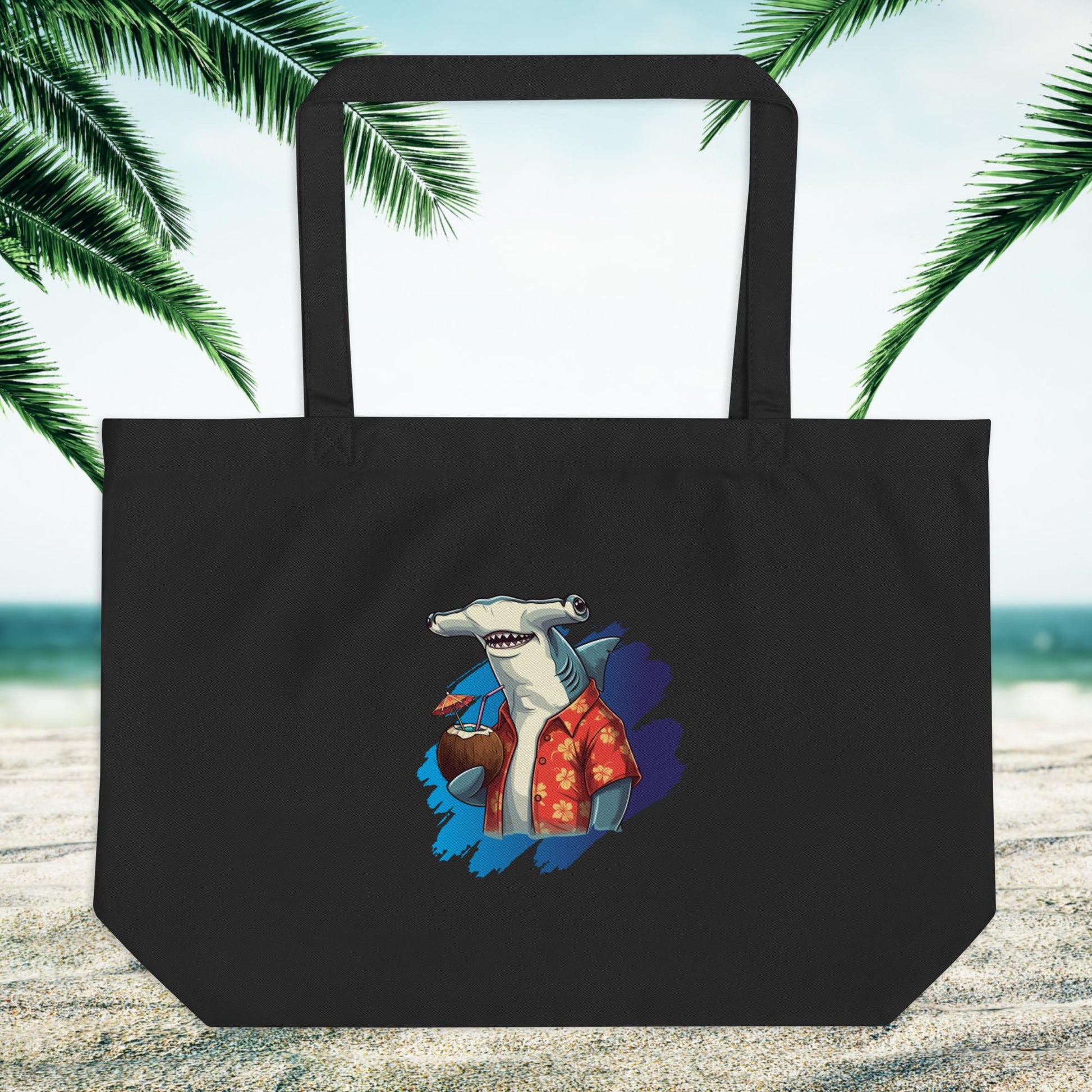 large black eco friendly tote bag with a hammerhead shark logo on a sandy beach