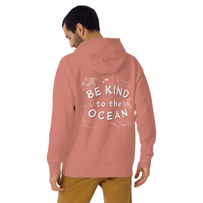 Man wearing a pink hoodie with the logo written be kind to the ocean with marine animals around it