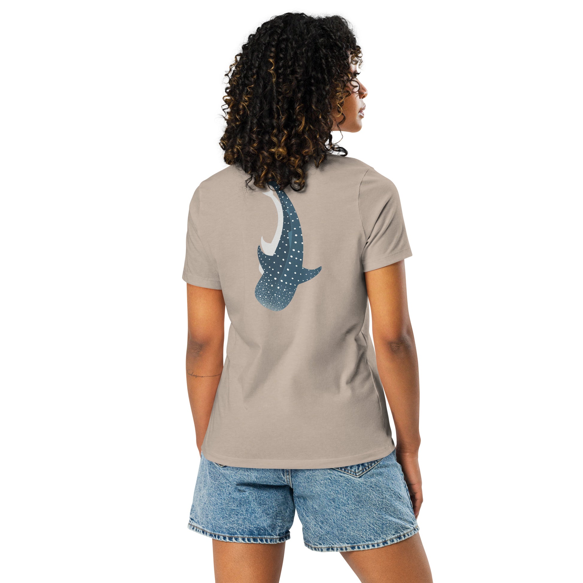 A woman wearing a beige shirt with a large logo of a whale shark pointing down on the back side